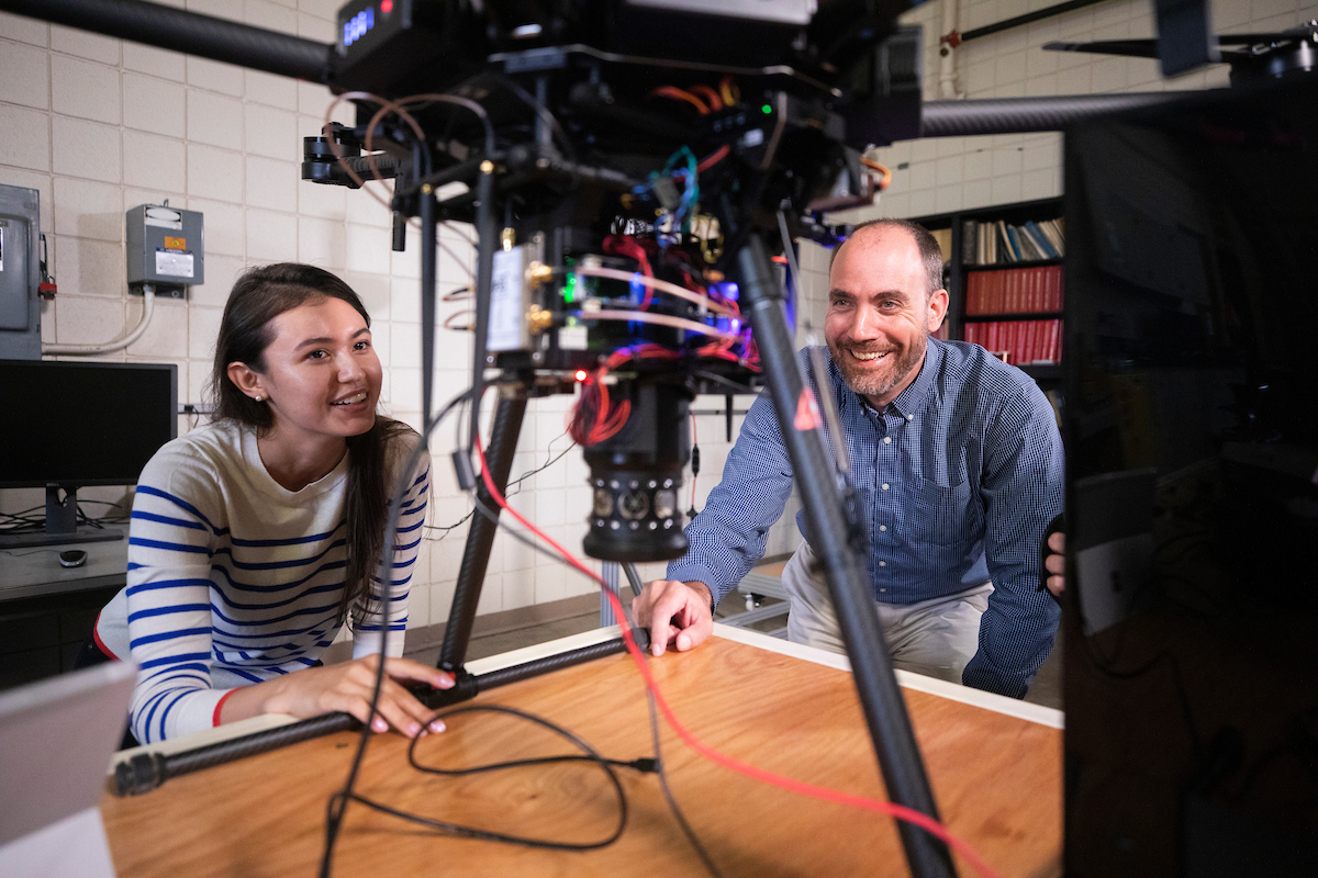 Female student with male professor looking at machine