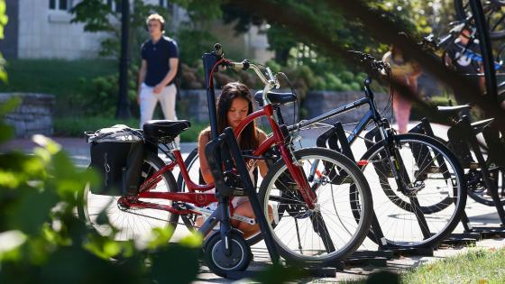 Female student securing bicycle on campus