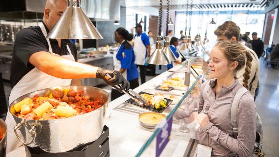 Dining staff distributing food during a special Mardi Gras themed event in the dining hall