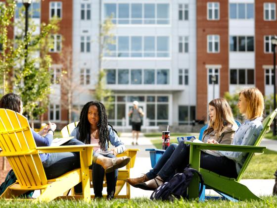 Students in Adirondack chairs in front of Boyd and Holmes Halls