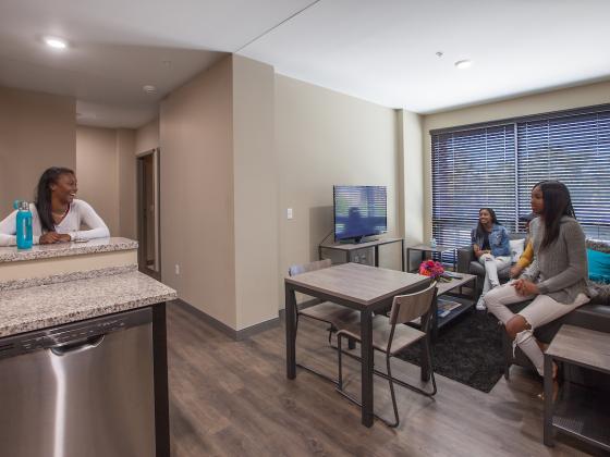 Three students gathering in common area of 4-Bedroom Apartment