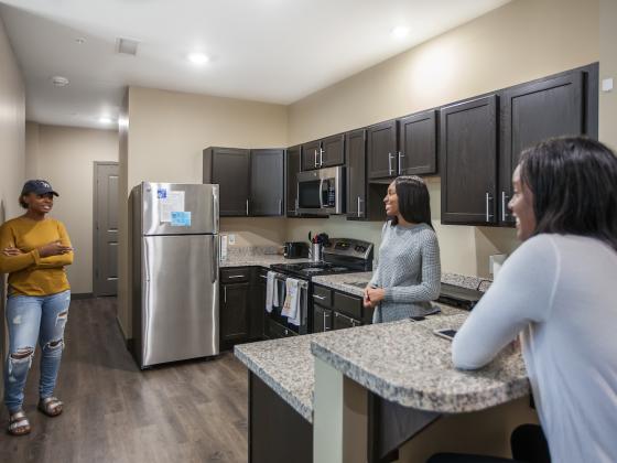 Three students hanging out in kitchen area of 4-Bedroom Apartment