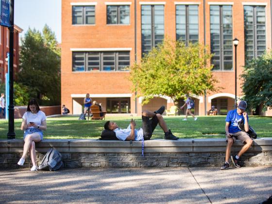 Students resting on brick wall between classes