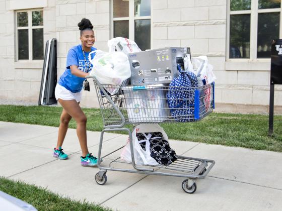 Female student pushing cart of student belongings